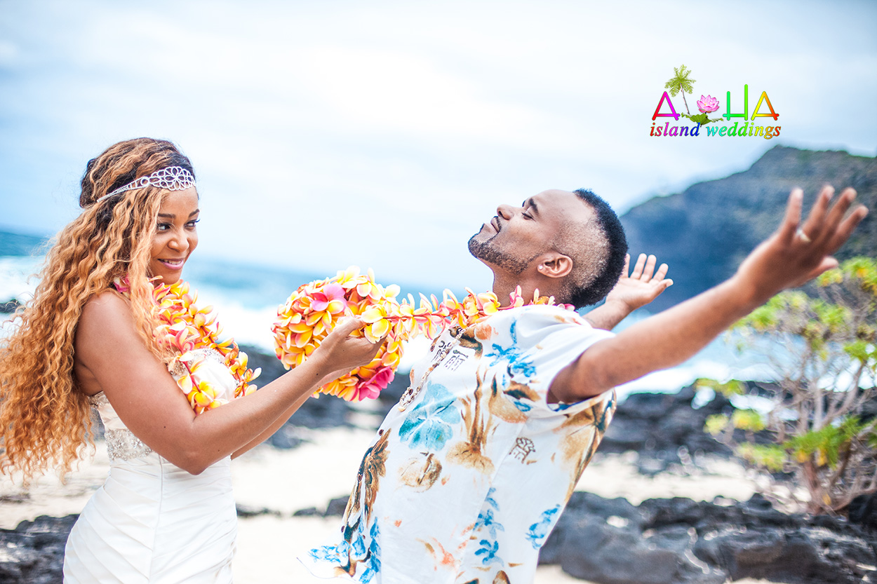 Pulling the flower leis on his neck the groom surrenders to her love while wearing the rainbow plumeria